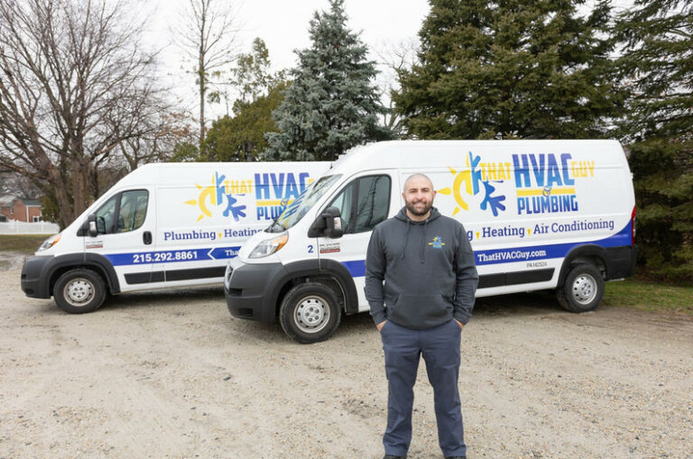 HVAC technician standing in front of service vans of That HVAC Guy & Plumbing